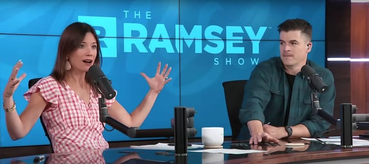Two people sit on the set of the Ramsey Show, speaking into mics and gesturing with their hands.