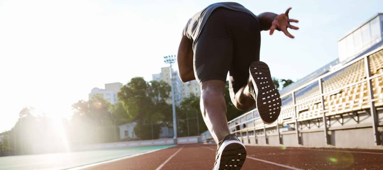 Back view of a young male athlete launching off the start line in a race