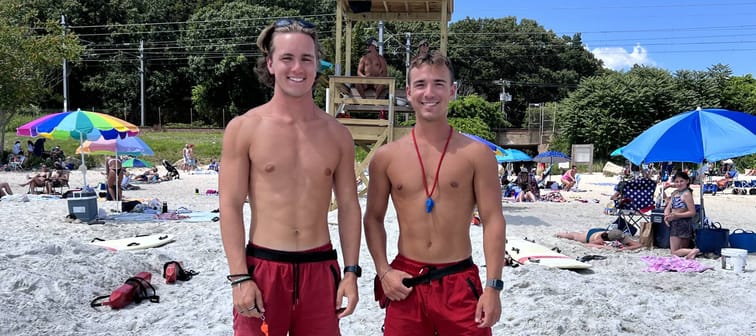 Two teen lifeguards smiling standing on a beach