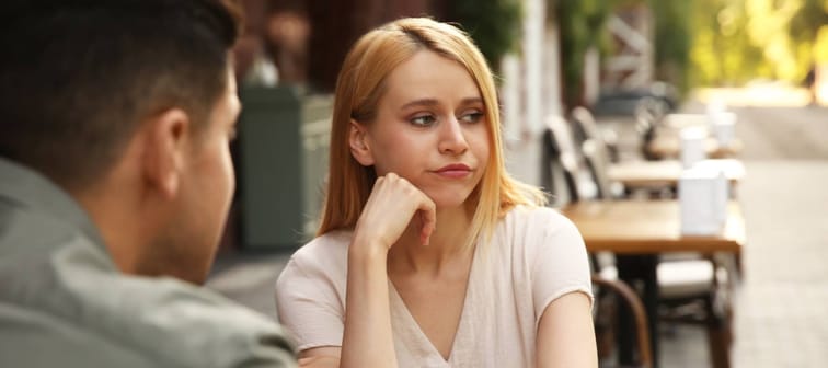 Young woman getting bored during first date with man at outdoor cafe.