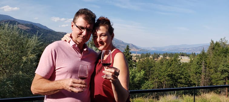 Older couple in late fifties traveling and enjoying outdoors with a glass of wine.