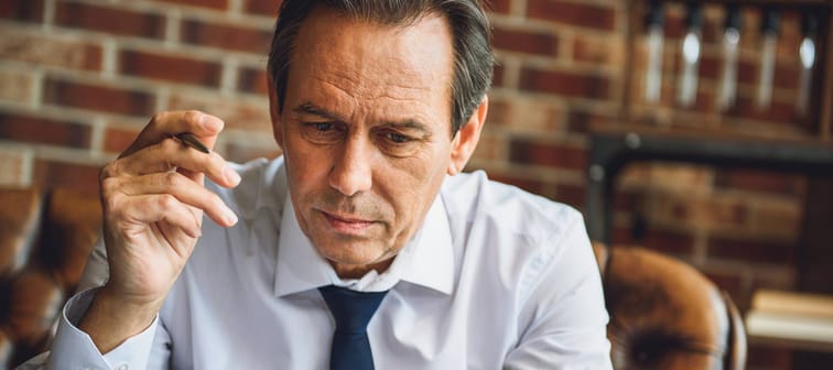 Concentrating older male person wearing tie, looking at papers.