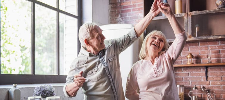An older couple dances in the kitchen.