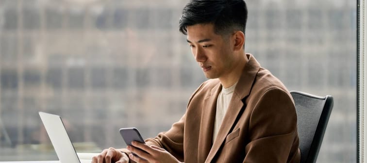 young busy smart serious Asian businessman holding cellphone device