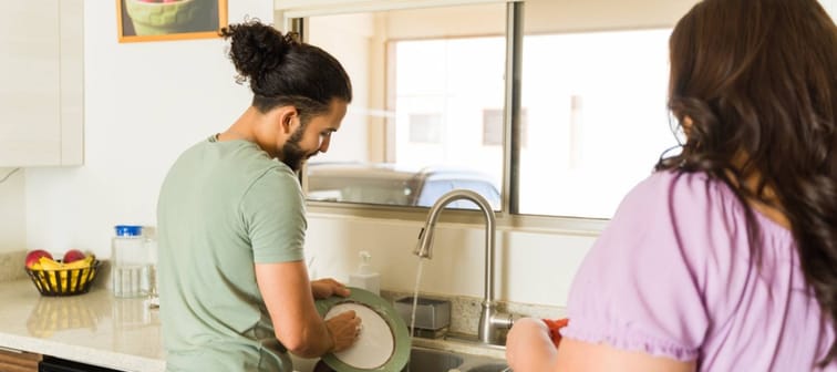 Couple seen from behind doing dishes together in a kitchen.