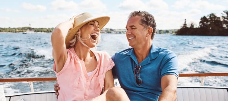 Couple seen laughing and smiling on a boat in the water.