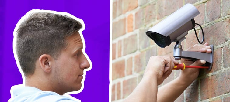 White man installing a video camera on the exterior of a house