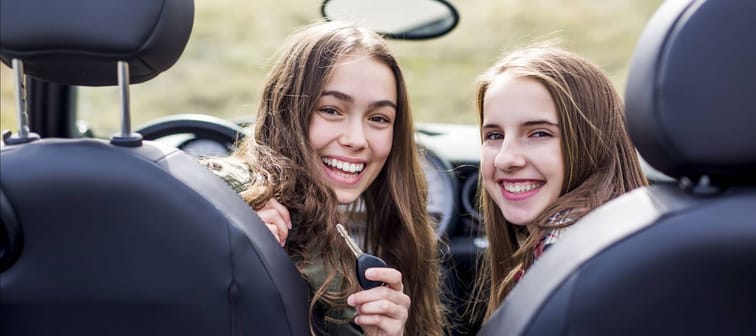 Teenage girl shows off brand new car key and car to her friend