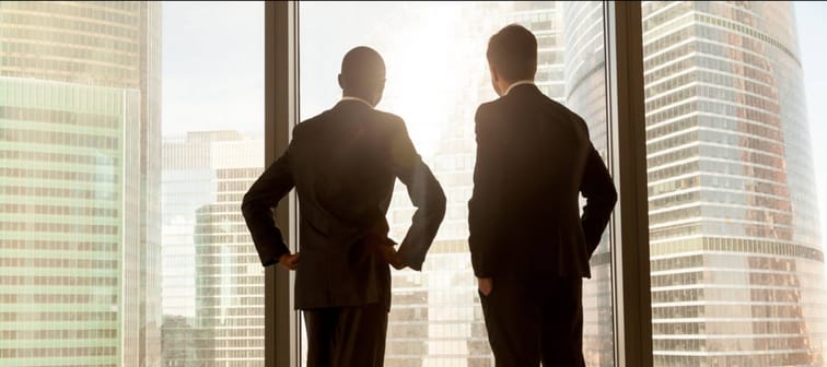 Wealthy men looking out an office window