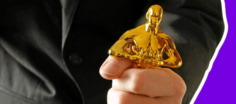close up of a white man's hand gripping an Oscar statuette