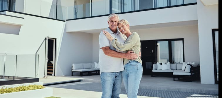 A retired couple embrace in front of their Florida real estate.