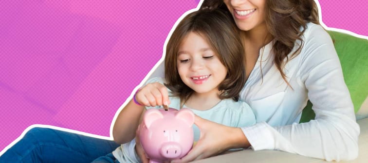 Mother and daughter putting coins into piggy bank while sitting on sofa