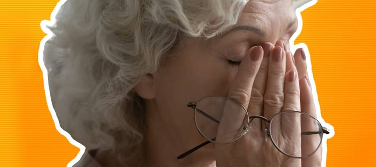 older woman looking tired and holding her hands up to her face