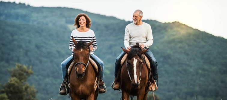 A senior couple riding horses.