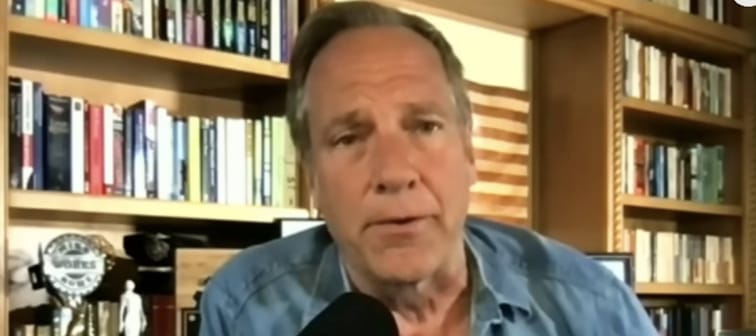 Mike Rowe seen in his home office, speaking into a microphone during television interivew.