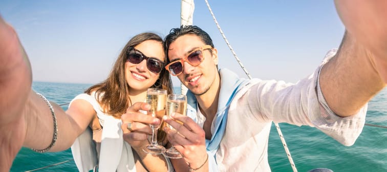 couple in love taking selfie on sailing boat cheering with champagne wine