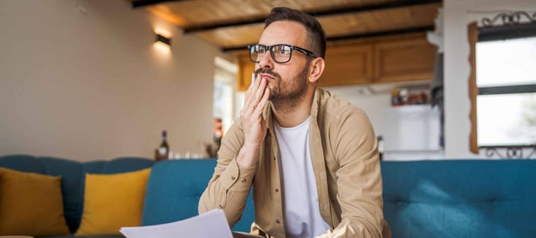 One man deep in thought at home holding important document.