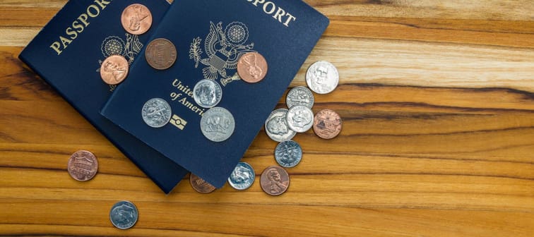 close up of two american passports and coins for a cheap travel concept