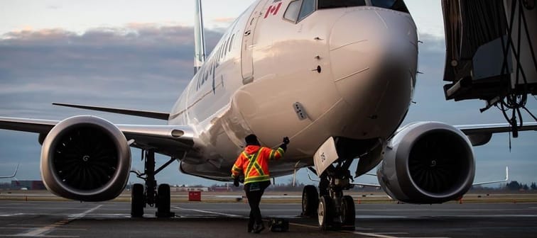A ground worker approaches a WestJet Airlines Boeing 737 Max aircraft after it arrived at Vancouver International Airport in Richmond, B.C., on Thursday, January 21, 2021. WestJet has issued 