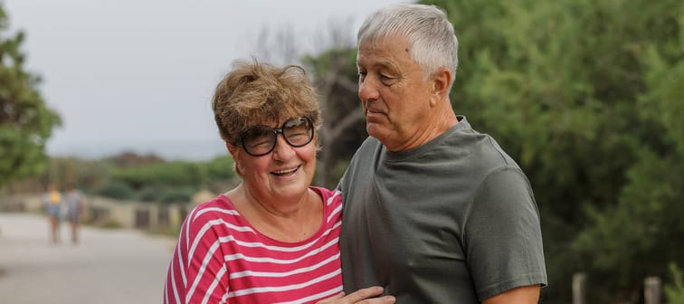 Happy older couple pose for a photo while on a walk outside.