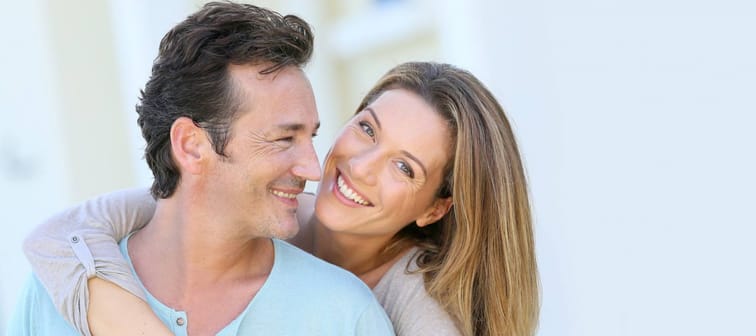 Middle-aged couple embracing in front of house