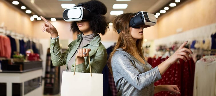 Two women in modern virtual reality headsets having expirience in shopping at lingerie store.
