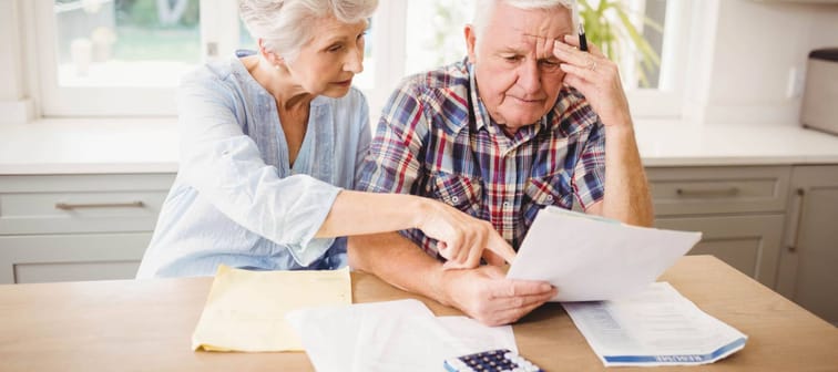 Worried senior couple checking their bills at home