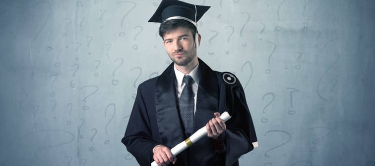Young graduate teenager with question marks drawn over his head
