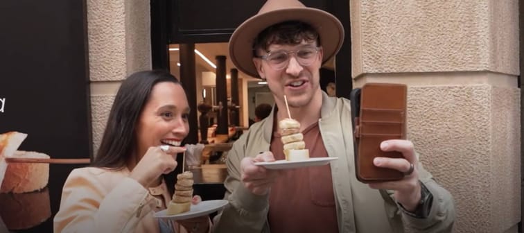 Couple pose for selfie in Spain, holding mushrooms on toast.