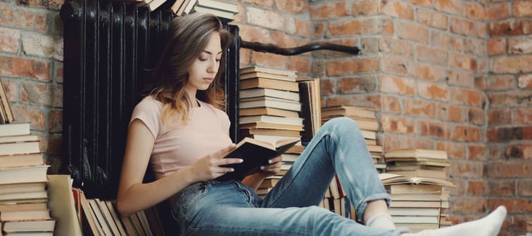 A woman reads a book while surrounded by many more.