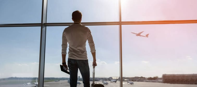 man watching a flight from an airport holding luggage