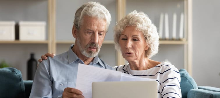 Happy elderly senior family couple reading paper correspondence or mails