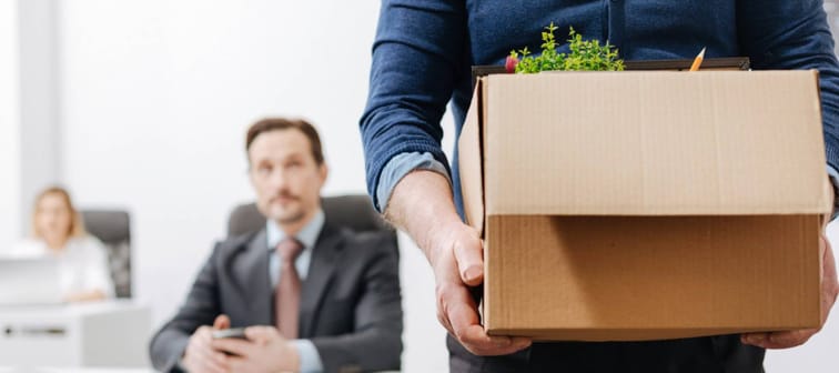 Employee quitting and walking out of office with box