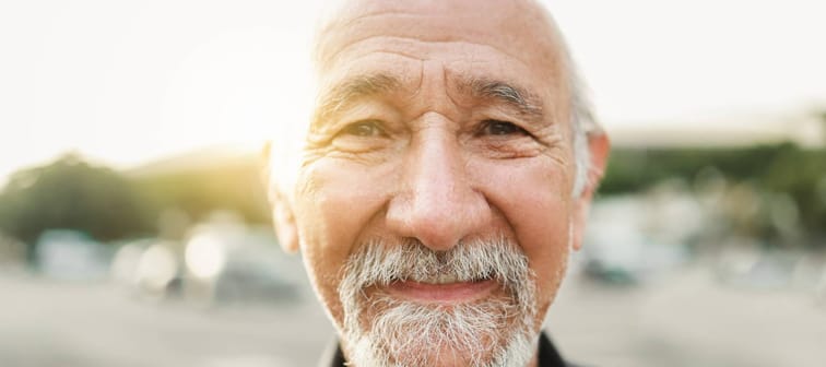 An older man smiles at the camera.