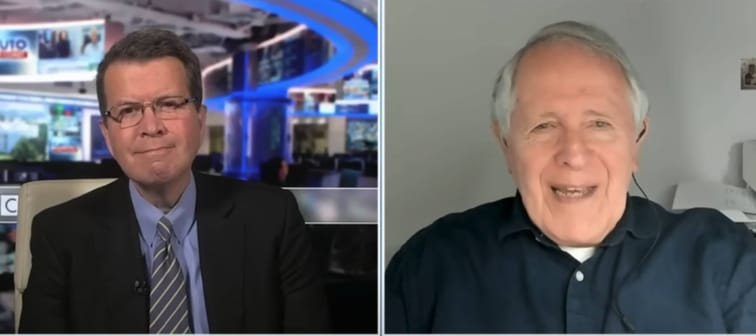 Two images of men talking, one in a suit seen in a newsroom, the other in a home office.