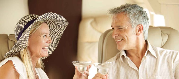 Bonding on a romantic getaway. Smiling and happy couple seated in a private jet and toasting each other.