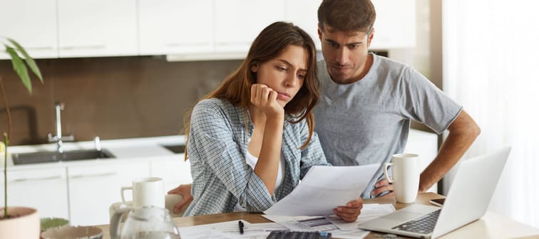 Picture of young wife and husband in kitchen having concentrated looks while reading loan application