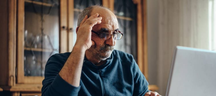 Senior man using a laptop while relaxing at home and exploring the internet.