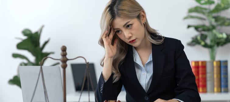 stressed Asian female lawyer with business contract paperwork