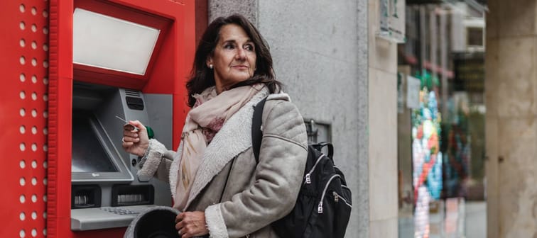 Woman with credit card in hand withdrawing money from automated teller machine