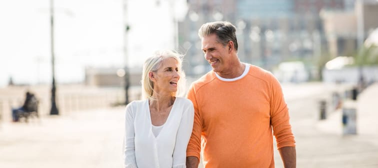 A middle-aged couple walks the boardwalk sharing strategies about what they should do with their money.