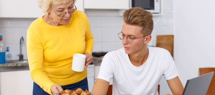 Senior woman taking care of her adult son and serving him cookies