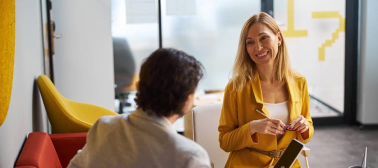 blonde woman keeping smile on her face while having pleasant conversation