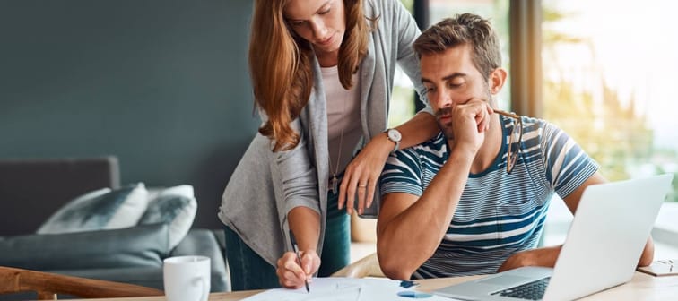 Couple, house and reading with laptop or documents for tax, expenses