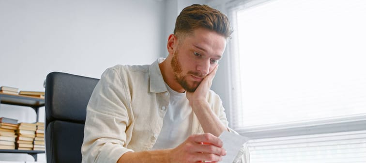 Young man looking at a receipt with a concerned expression