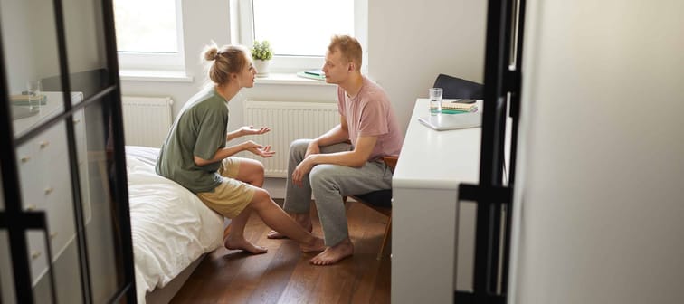 young Caucasian couple discussing problem while sitting opposite one another in bedroom