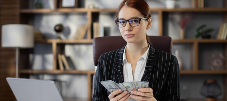 business woman working on laptop counting money cash