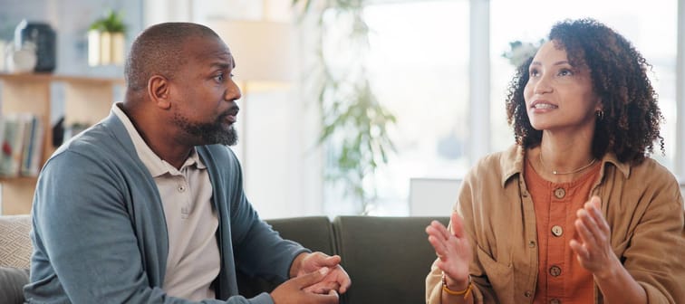 a middle-aged Black couple argue on a couch