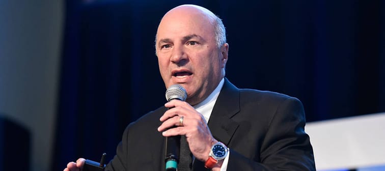 Investor and TV personality Kevin O'Leary of the show "Shark Tank" speaks into a microphone, gesturing and looking intent.