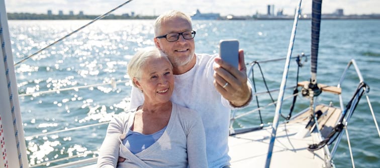 seniors with smartphone taking selfie on yacht